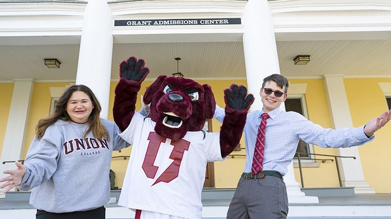 Two admissions representatives stand outside with Charger, the official mascot of Union College.