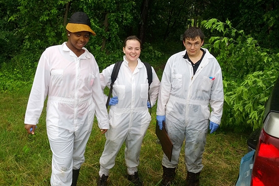 White coveralls make it easier for students working with Biology Professor Kathleen LoGiudice to spot ticks on their clothing. Tasha Scott '15, Colleen Cook '14 and Dan Rice '14, shown here, had just been drenched by a sudden thunderstorm.