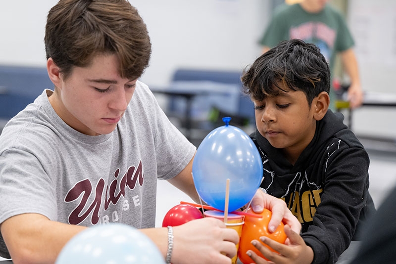 A student and child looking at a balloon.