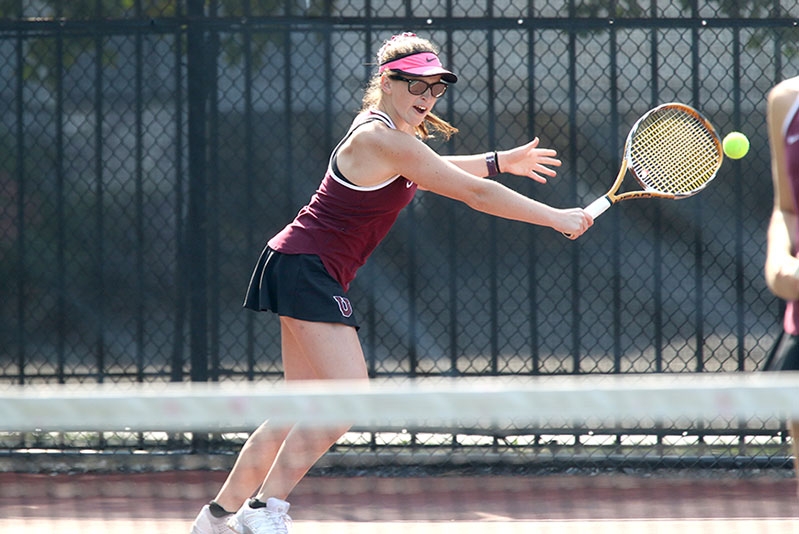  A member of the women's tennis team practices her backhand.