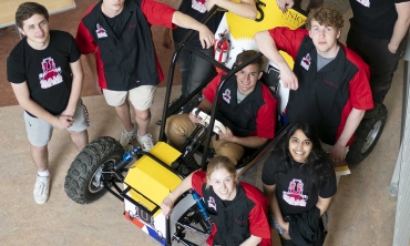 Students proudly showcase the vehicle they've engineered as part of their research in the field of engineering