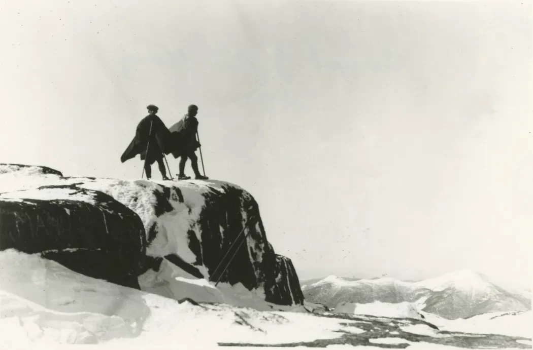 photo of two early hikers on a mountaintop in winter