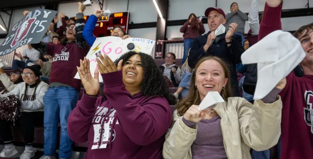 Union students wearing Union gear, cheering at a hockey game at M&T Bank Center arena.