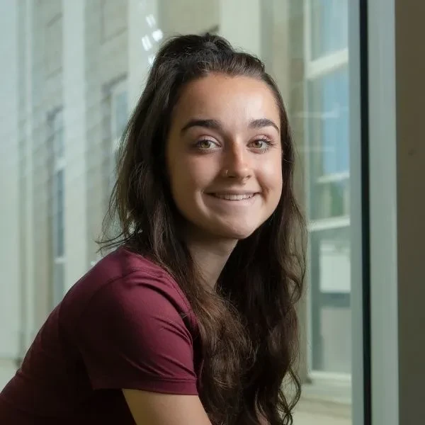 Grace Nicol '24, sitting inside ISEC, smiling at the camera.