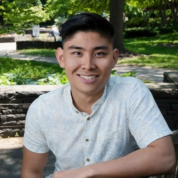 Ryo Hashimoto ’24, sitting in Jackson's Garden, smiling.