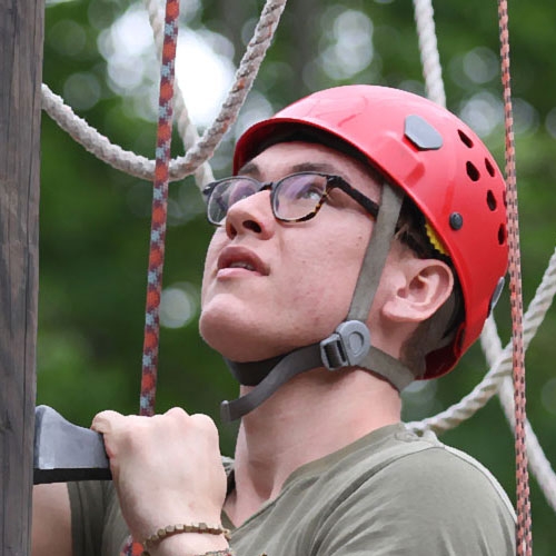 A Union student  rappelling up a tree