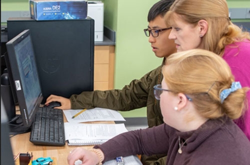 A photo of students looking at a computer