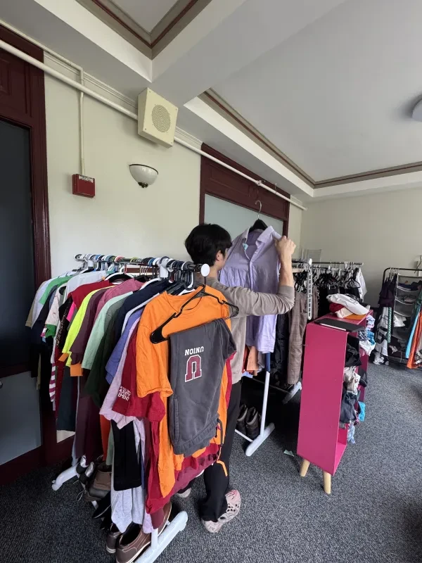 Student looking through an arrangement of clothing at campus thrift store.