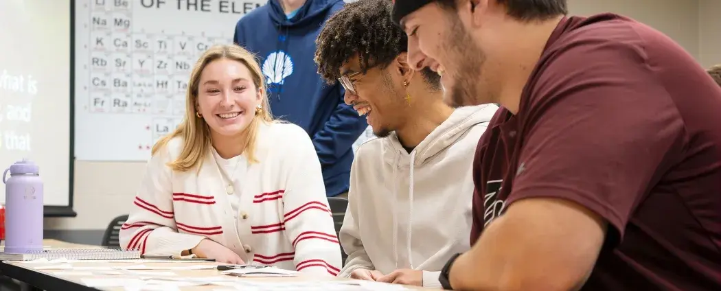 Students inside a civil engineering classroom are smiling, studying, and engaging in conversation.