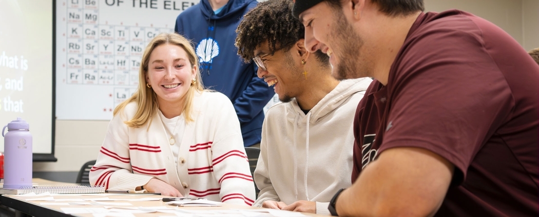 Students inside a civil engineering classroom are smiling, studying, and engaging in conversation.