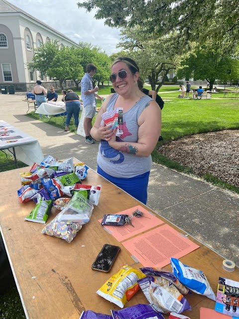 Dr. Jen Mitchell, Associate Professor of English at Union College, stands at a Pride Fest table.