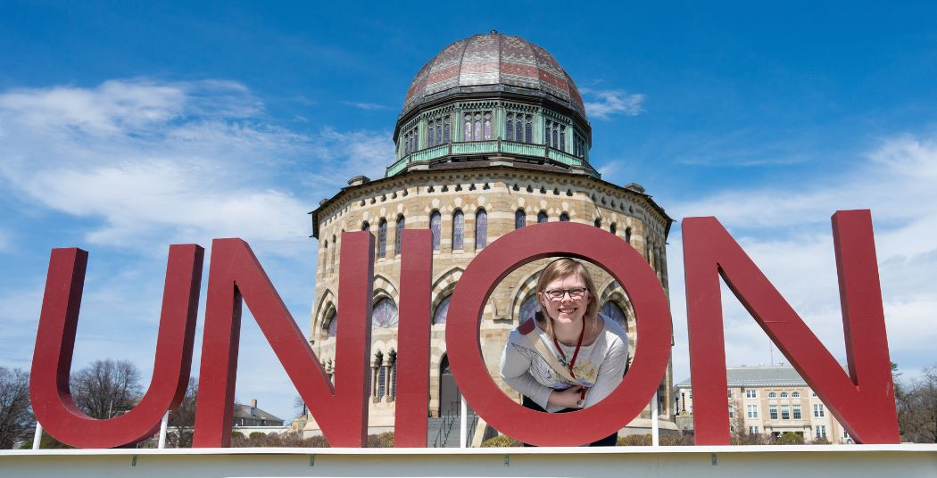 Admitted student posing behind the UNION letters in front of the Nott.