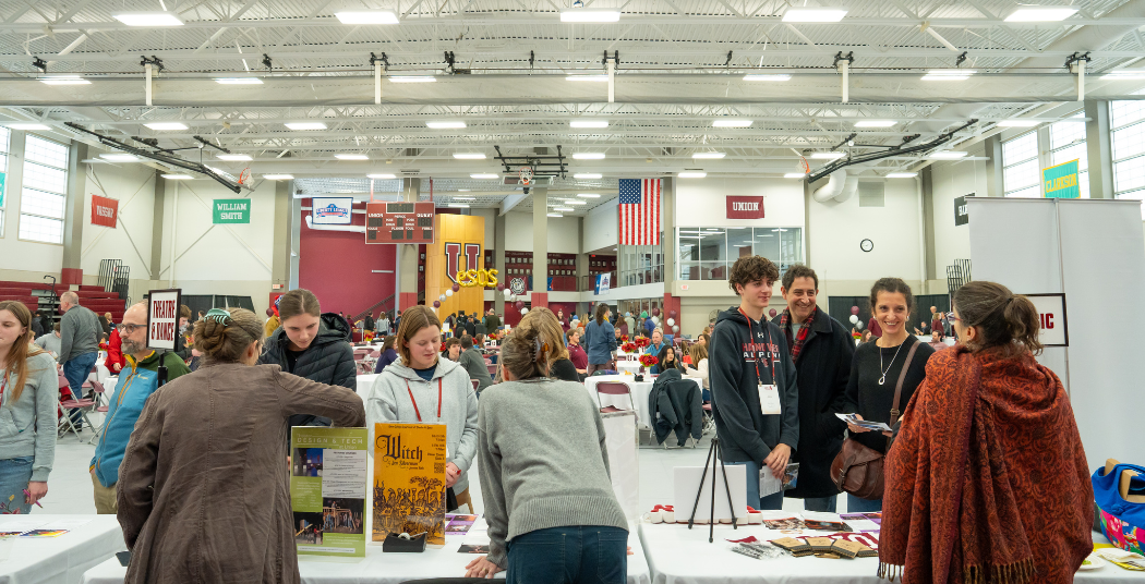 Admitted students asking faculty members questions at an open house.