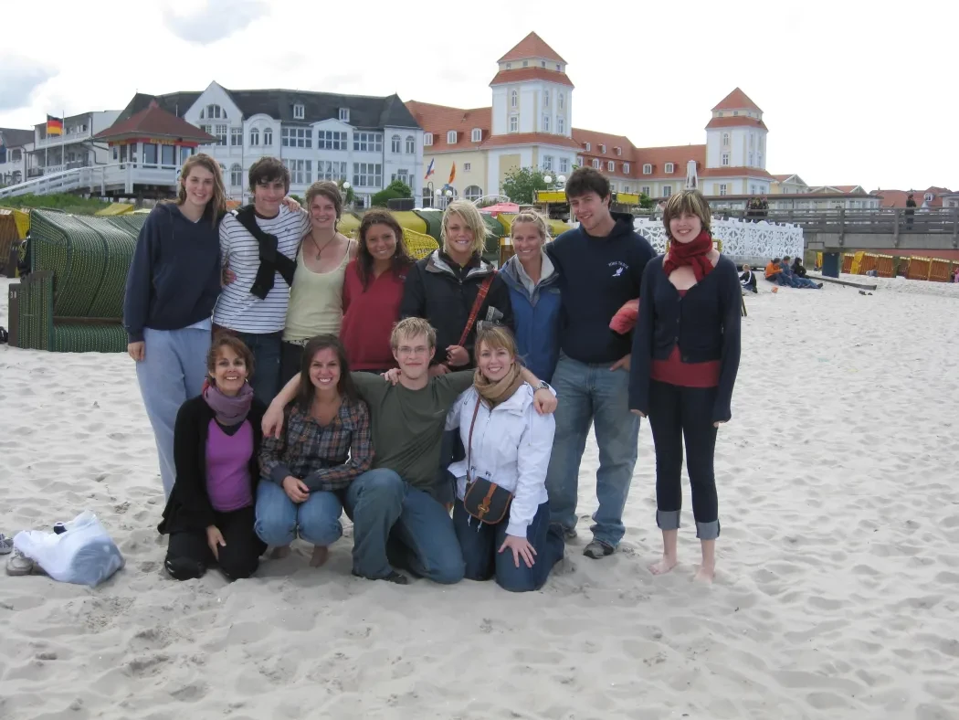 Photo of students with Prof Bell huddled together on a beach on the Baltic Sea.