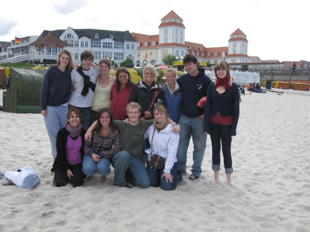 Photo of students with Prof Bell huddled together on a beach on the Baltic Sea.