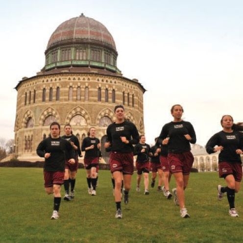 Women soccer team running in front of the Nott Memorial