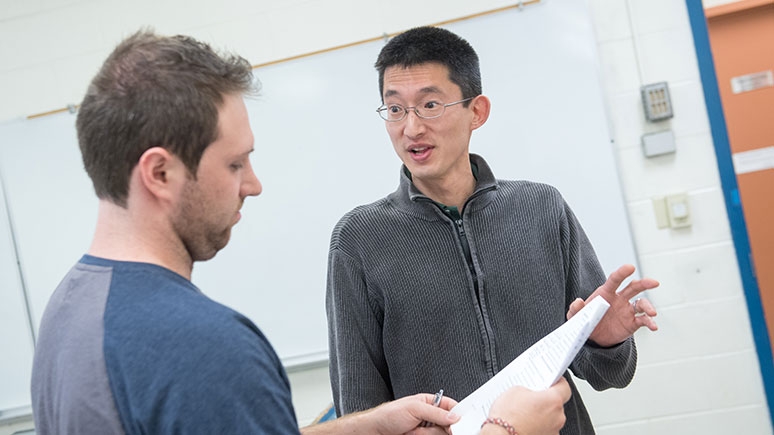  Takashi Buma, the associate professor of electrical, computer, and biomedical engineering, in conversation with a student on the right.