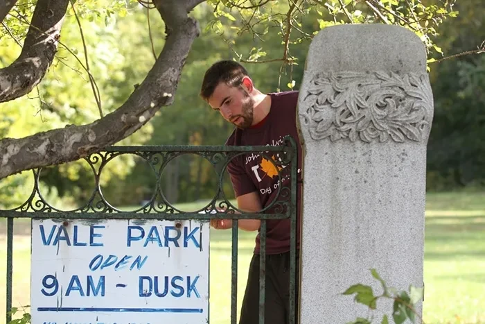 A student volunteer painting a fence in Vale Park, Schenectady