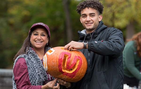 A family enjoys showing off their carved pumpkin at Homecoming and Family Weekend 