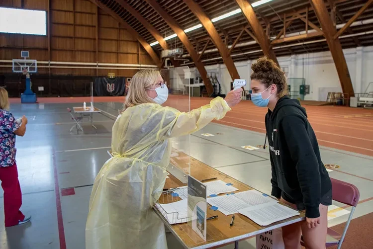 Celeste Beaudoin ’24 has her temperature checked by registered nurse Joan Thompson in the&nbsp;COVID-19 testing site in Memorial Field House.&nbsp;