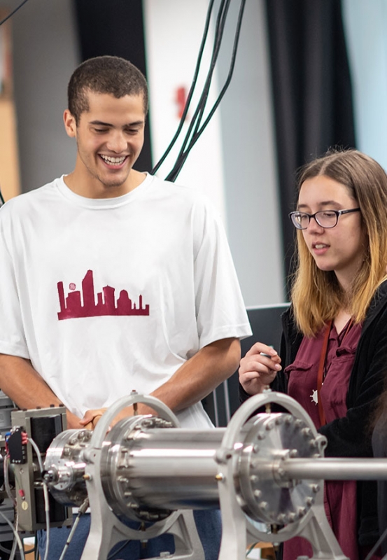 Jackson Selent '22 amd Mia Villeneuve '22 work on the particle accelerator.