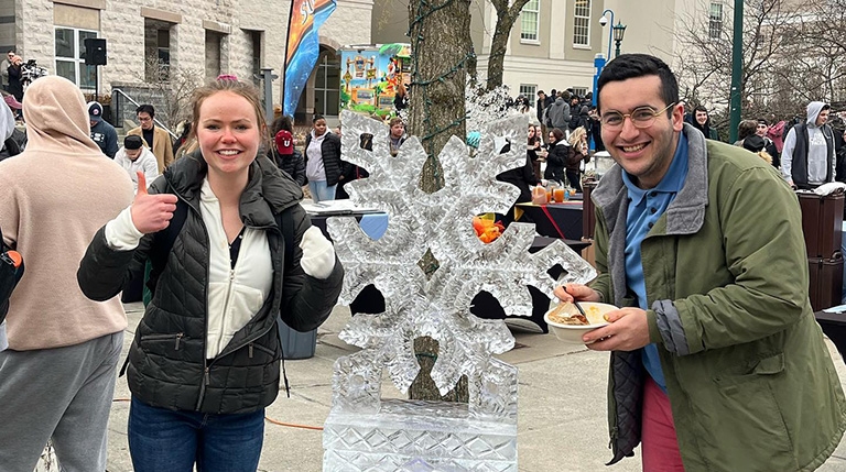 Two students pose next to an ice sculpture