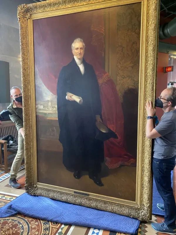 Members from the Williamstown Art Conservation Center carefully prepare a portrait of longtime Union President Eliphalet Nott for a temporary move from the Nott Memorial while the building undergoes roof repairs. At 8-feet-by-5-feet and weighing nearly 100 pounds, the painting by&nbsp;renowned artist Henry Inman is the College’s largest painting.