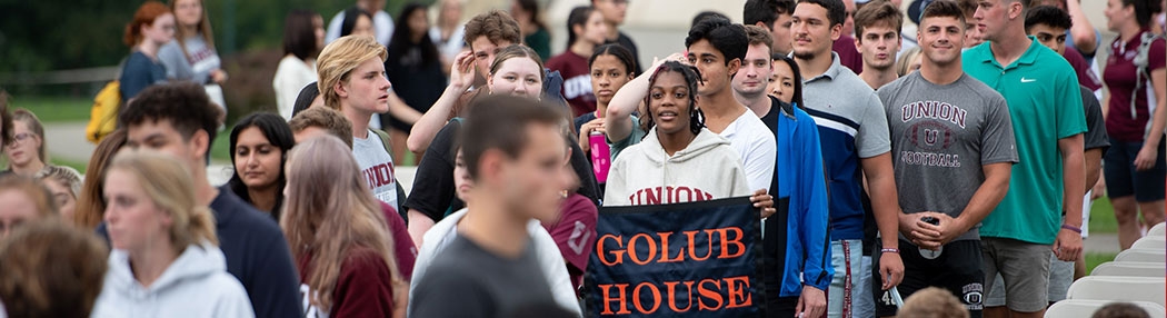 A student holds a Golub House sign at Convocation 2021