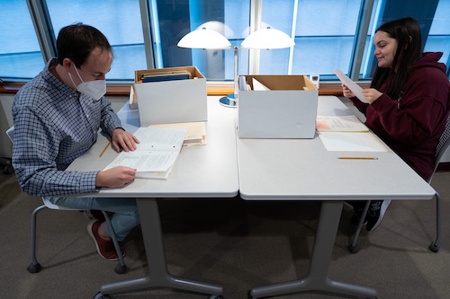 Joe Lueck, left, outreach and reference archivist for Special Collections and Archives at Schaffer Library, and Madeline Rioux '23 sort through the papers of author Andrea Barrett '74.