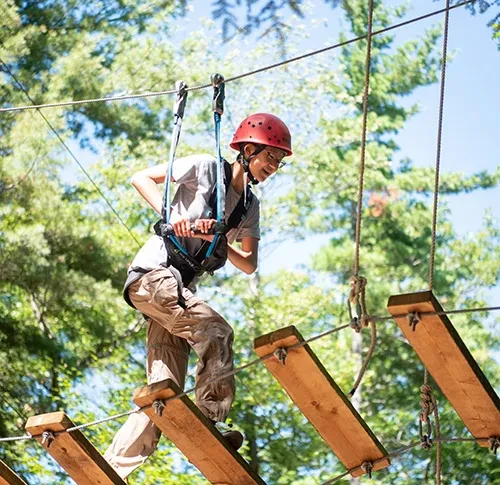 A student on a rope ladder that is part of an obstacle course