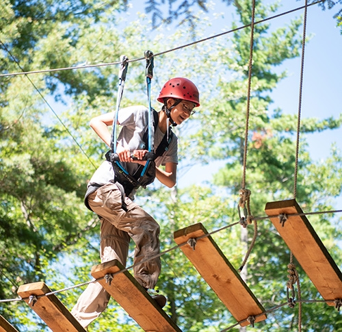 A student on a rope ladder that is part of an obstacle course