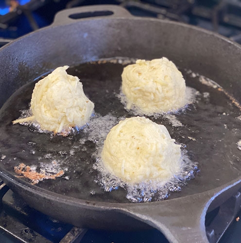 Latkes frying in a cast iron skillet