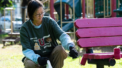 A student painting a bench 