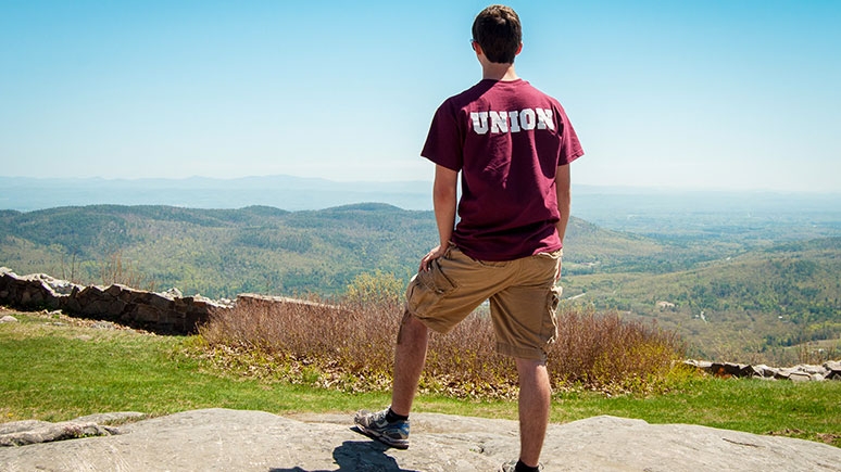 A Union student on a ledge surveying the mountains in the distance.