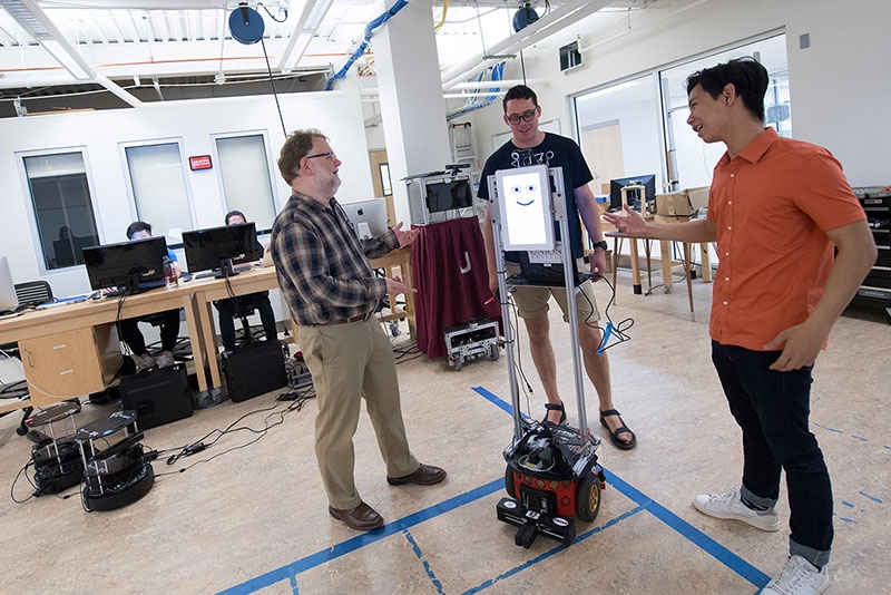 A view of a faculty member, students and robot in the CROCHET Lab