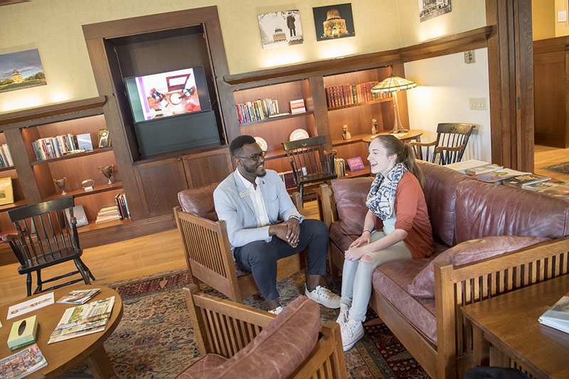 A prospective student and admissions officer chat in Grant Hall parlor.