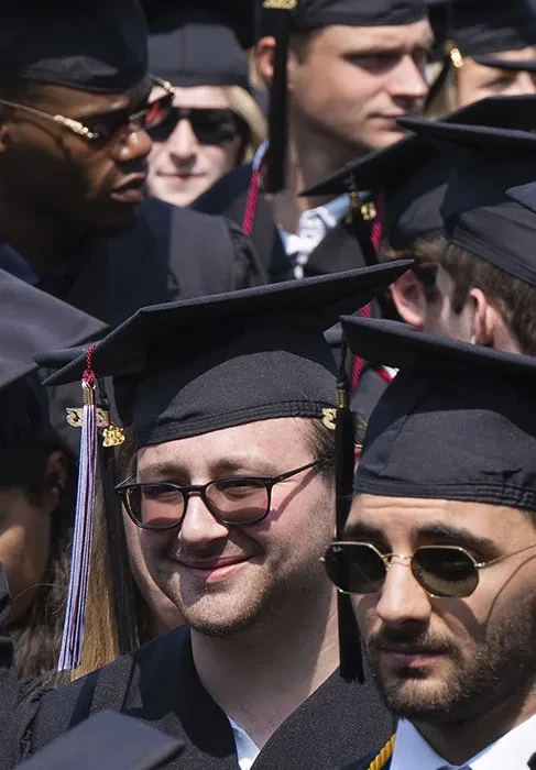Graduates smile as they listen to the featured speaker's comments.