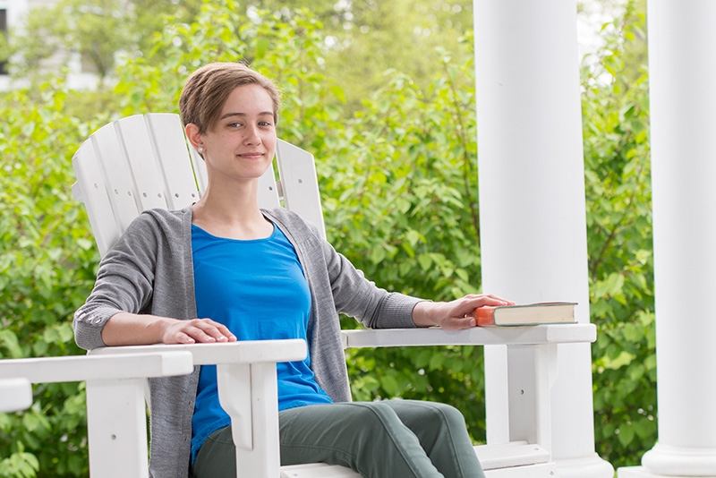 Meghan Reilly '20 siting in a rocker on the Lamont House porch.