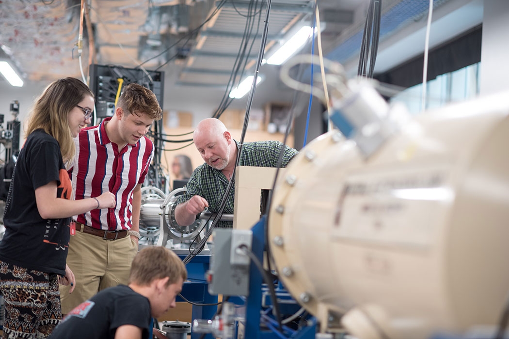 Students and faculty working around the particle accelerator in the basement of ISEC.