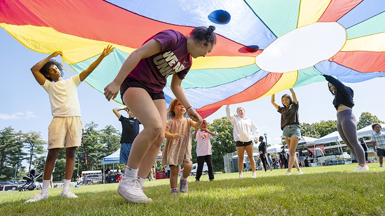 Students engaged in a fun activity that involves getting underneath a giant parachute.