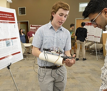 A student at Steinmetz poster session demonstrates an arm cast that makes use of artificial intelligence
