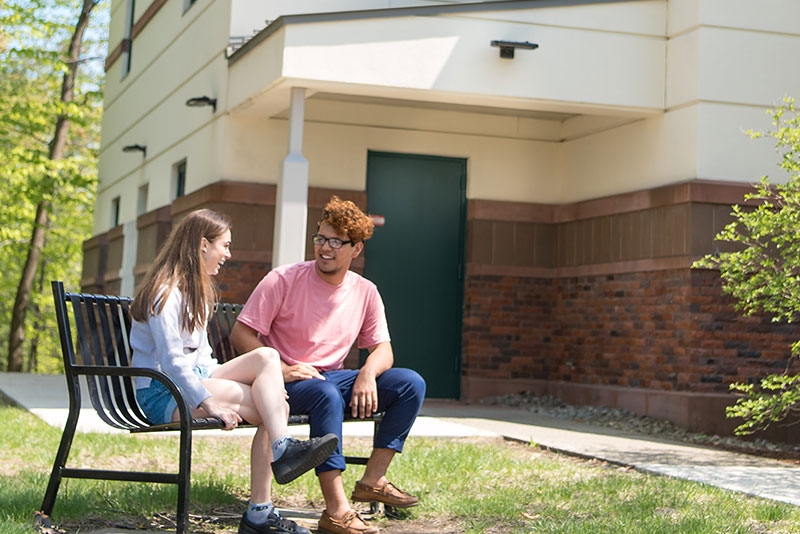 Two students conversing on a bench outside Yulman Theater