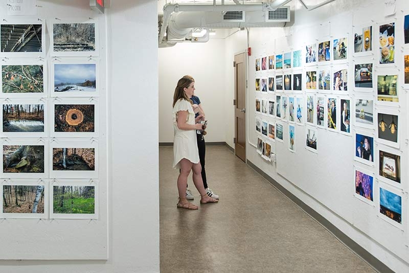  Students examining artwork in a display area at the college.