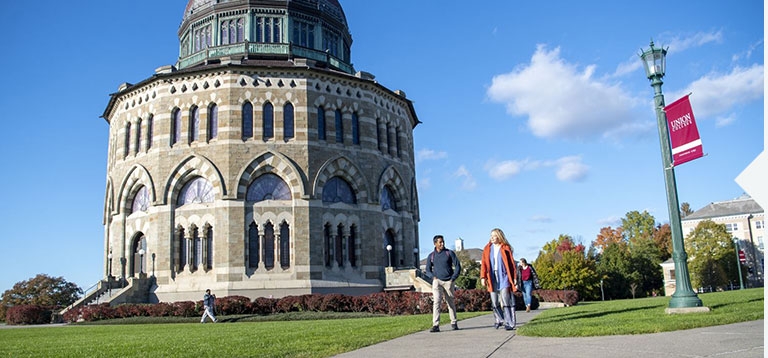 Students walking across campus with the Nott Memorial visible in the background