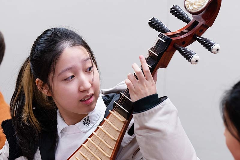 A student playing a guitar-like instrument.