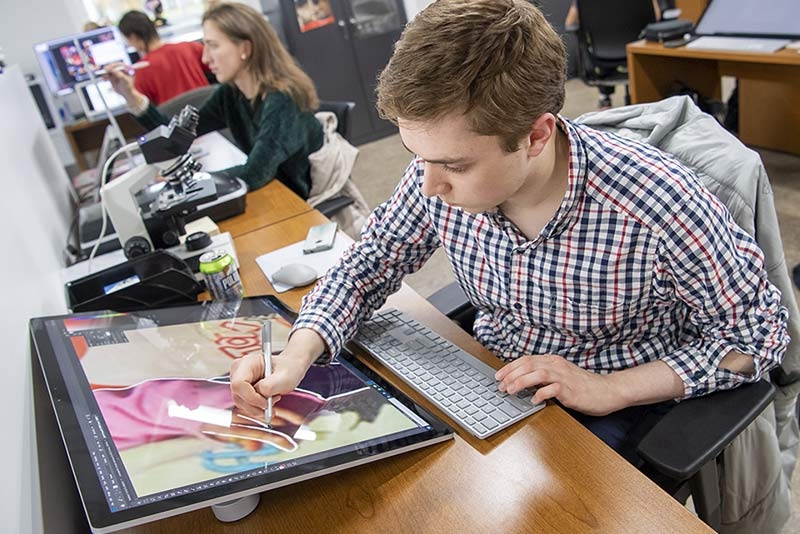  A student using a digital stylus to create a drawing on an electric display screen.