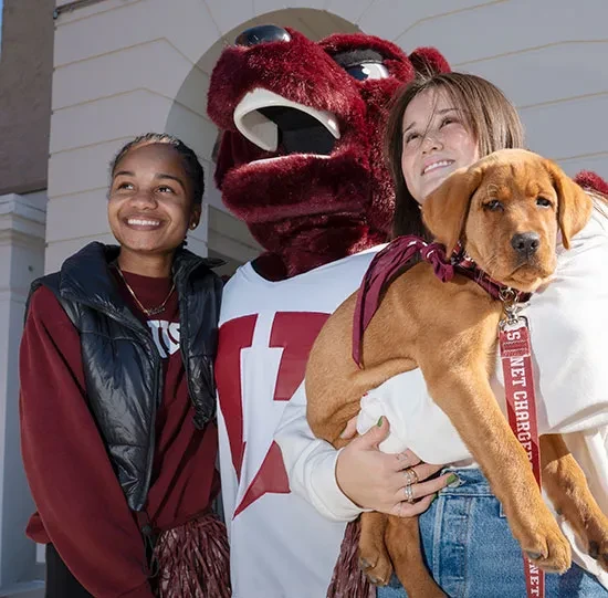 Students pose with the costumed mascot and the puppy.