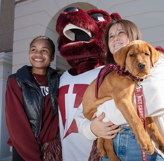 Students pose with the costumed mascot and the puppy.