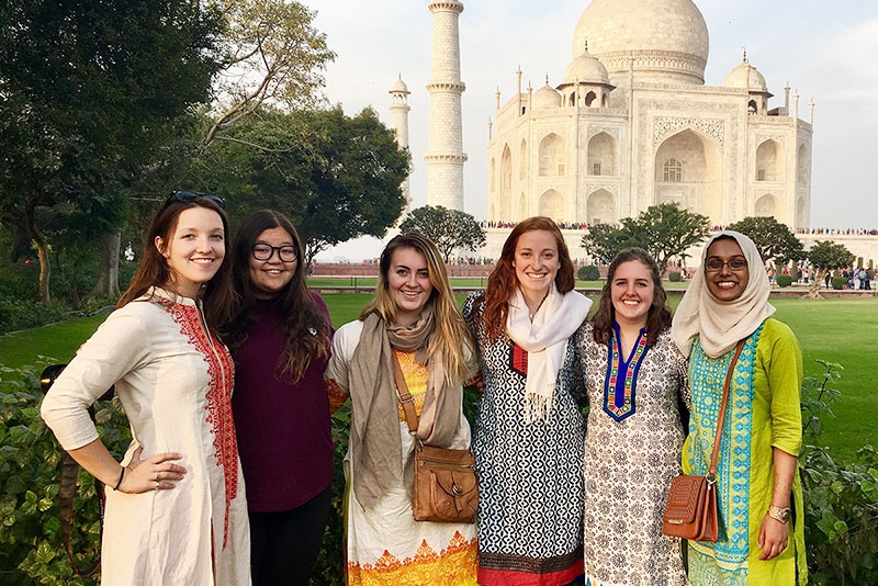A group of students pose for pictures with the famous Taj Mahal in the background.