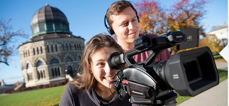 The Nott Memorial is in the background as two students operate a video camera
